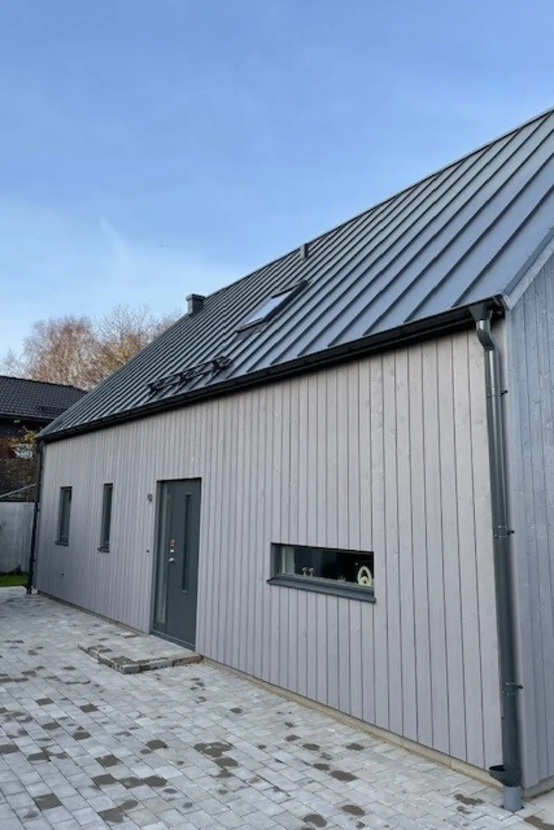 Modern villa i Båstad med grå träpanel och plåttak